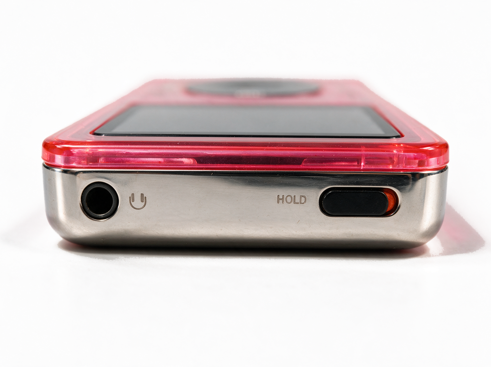 Static &mdash; top edge, headphone jack and hold switch, translucent neon pink iPod Classic.
